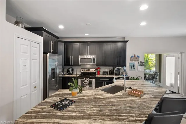 a kitchen with kitchen island granite countertop a sink stove and refrigerator