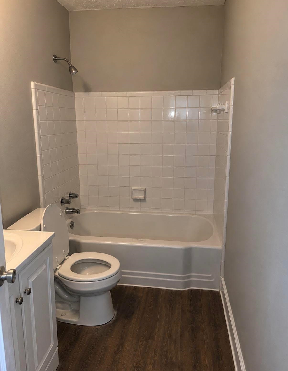 1510 Gausco Road Memphis, TN 38106 - Photo 6 of 10 Bathroom featuring a white subway tile tub surround, white bathtub, wood-finish flooring, and a white vanity with a countertop sink