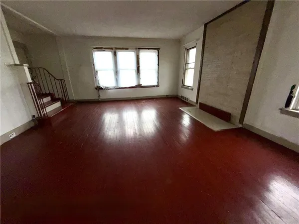 an empty room with wooden floor and windows with curtains