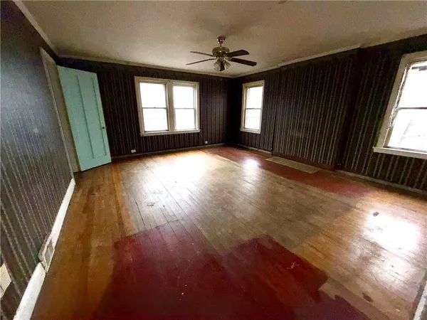 an empty room with wooden floor and windows