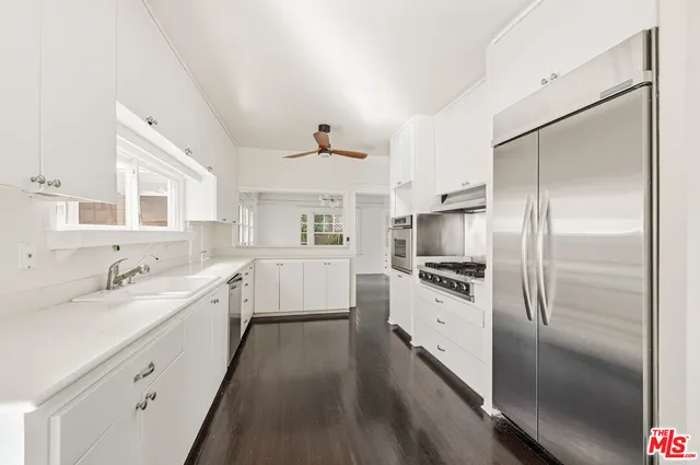 a large white kitchen with a refrigerator a sink a stove and white cabinets