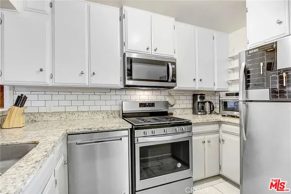 a kitchen with granite countertop white cabinets sink and stainless steel appliances