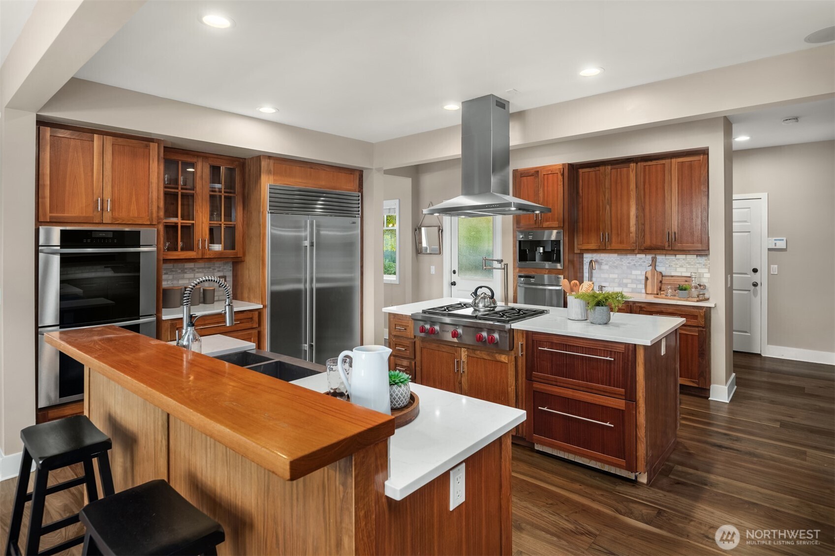 26133 Northeast 34th Street Redmond, WA 98053 - Photo 15 of 40 a kitchen with stainless steel appliances granite countertop a stove a refrigerator a sink a dining table and chairs with wooden floor