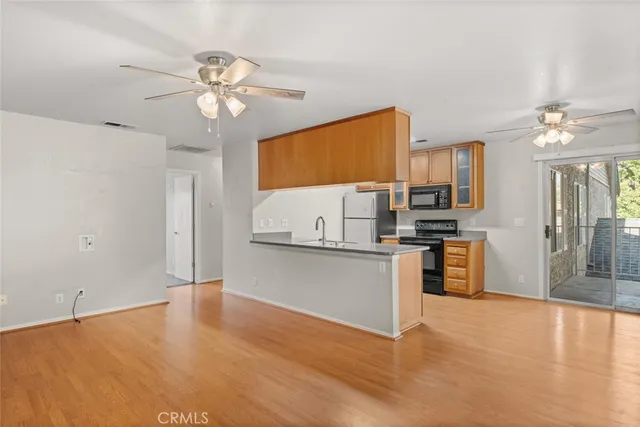 a open kitchen with stainless steel appliances a stove top oven a refrigerator cabinets and wooden floor