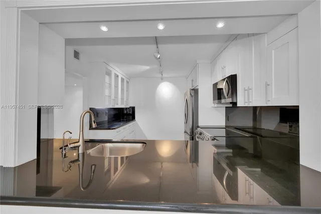 a kitchen with a sink a counter top space cabinets and stainless steel appliances