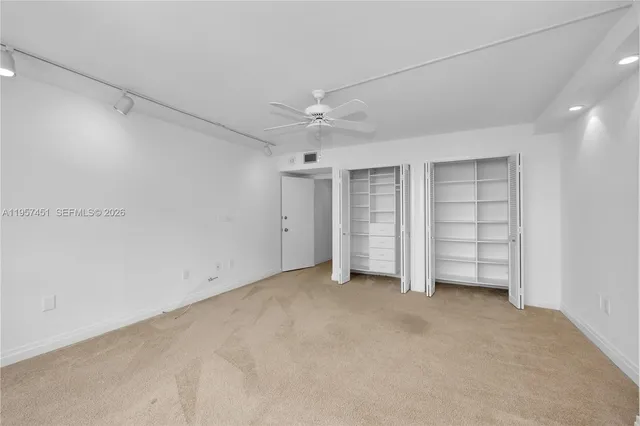 an empty room with a ceiling fan and window