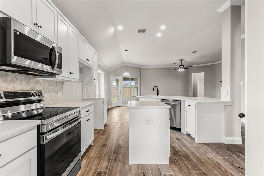 314 Pennington Road Josephine, TX 75173 - Photo 5 of 37 a kitchen with stainless steel appliances a stove top oven a sink dishwasher and white cabinets with wooden floor