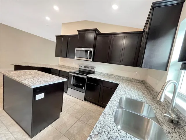 a kitchen with kitchen island stainless steel appliances a sink stove and refrigerator