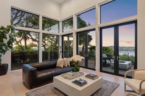 a living room with furniture large windows and wooden floor