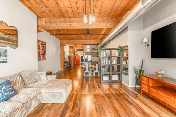 a living room with stainless steel appliances furniture and a flat screen tv