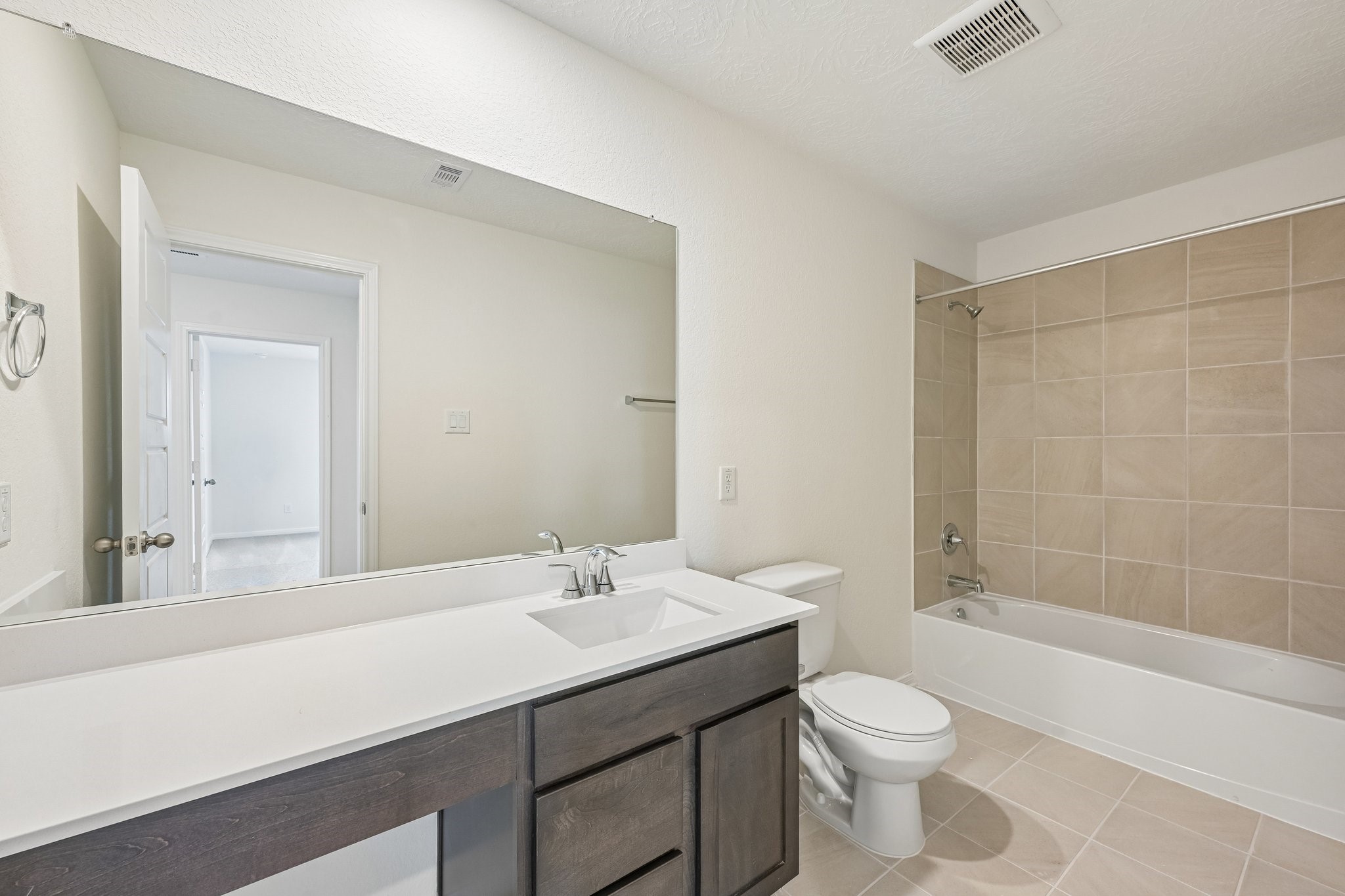 2503 Spruce Hl Road Beasley, TX 77417 - Photo 17 of 25 The secondary bathroom offers tile flooring, a bath/shower combination with a stylish tile surround, rich stained wood cabinetry with added knee space and elegant light countertops, a mirror, and sleek fixtures with modern finishes.