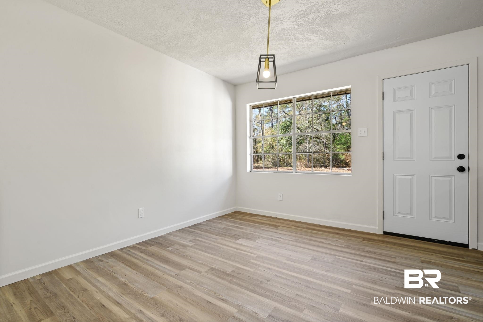 910 Moran Street Bay Minette, AL 36507 - Photo 15 of 20 Unfurnished dining area featuring light wood-style floors and a textured ceiling