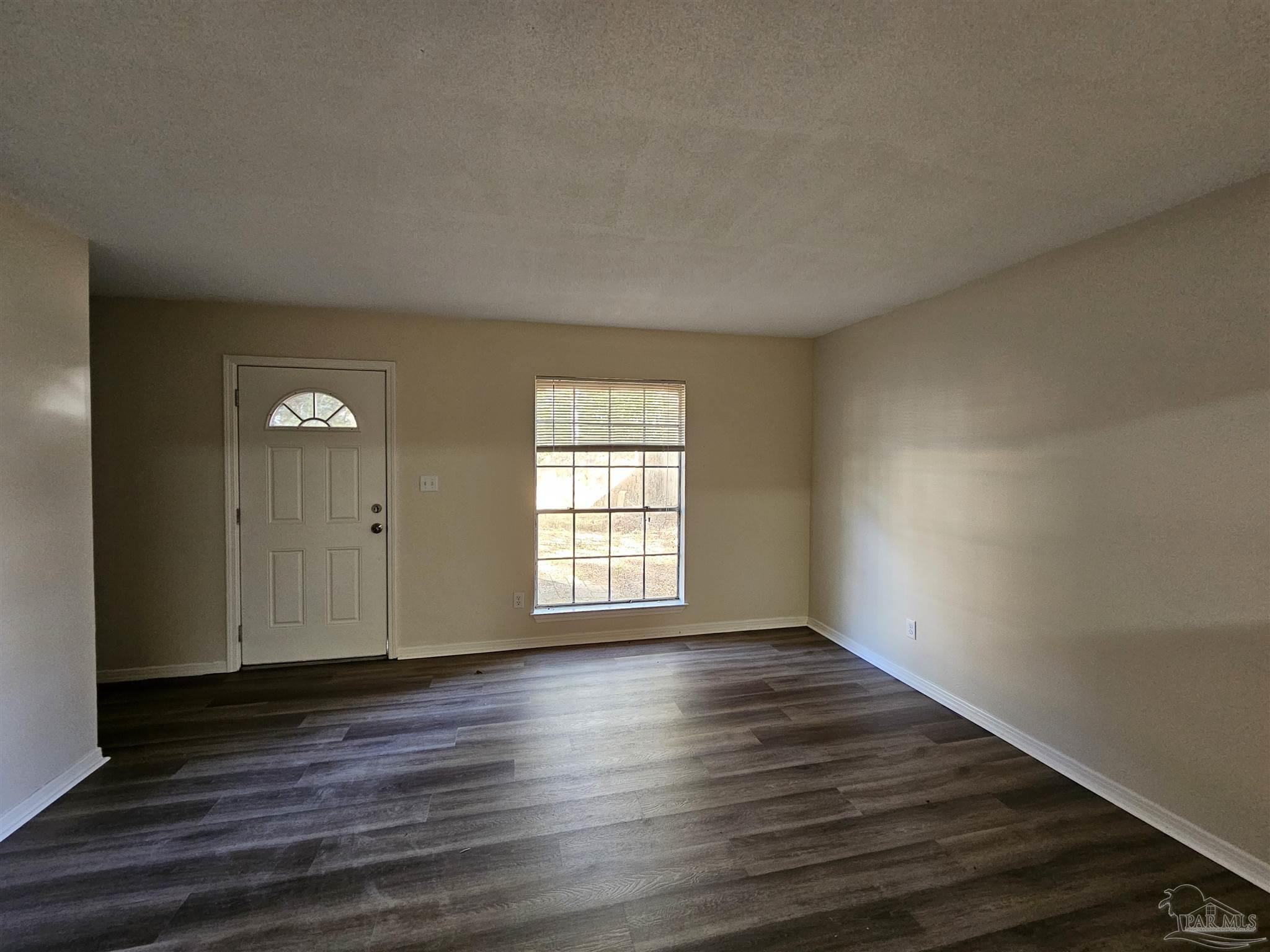 3689 East Olive Road Pensacola, FL 32514 - Photo 2 of 6 an empty room with wooden floor and windows