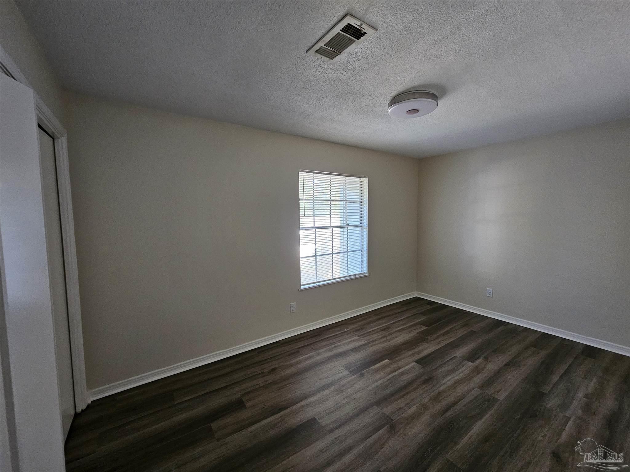 3689 East Olive Road Pensacola, FL 32514 - Photo 5 of 6 an empty room with wooden floor and windows