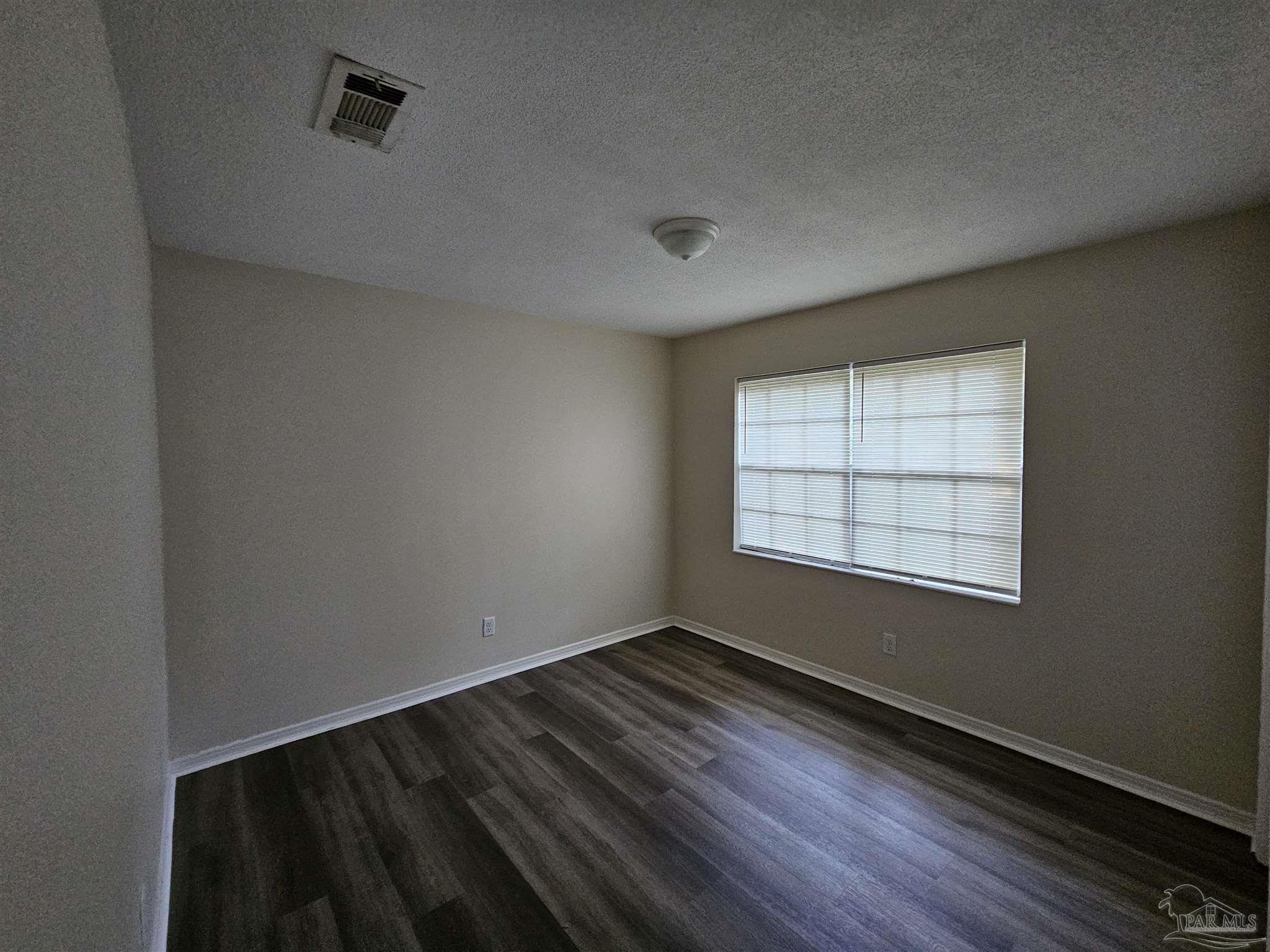 3689 East Olive Road Pensacola, FL 32514 - Photo 6 of 6 an empty room with wooden floor and windows