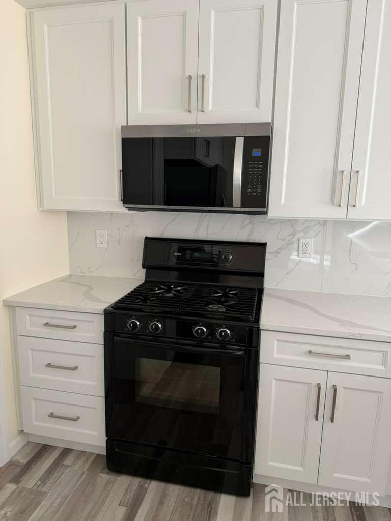126 Winchester Way Somerset, NJ 08873 - Photo 12 of 33 a kitchen with white cabinets and black appliances