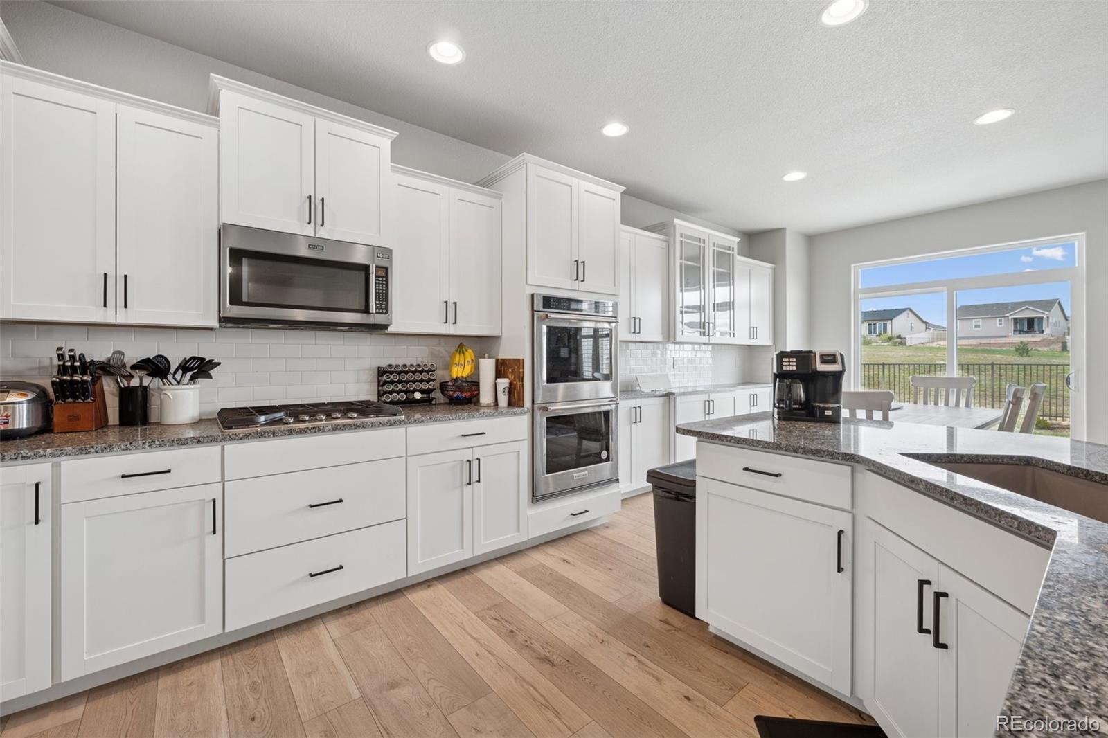 12846 Granite Ridge Drive Peyton, CO 80831 - Photo 13 of 32 a kitchen with granite countertop white cabinets white stainless steel appliances with a sink and dishwasher