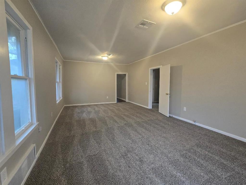 1126 West 6th Avenue Corsicana, TX 75110 - Photo 3 of 12 Unfurnished room featuring dark carpet and ornamental molding