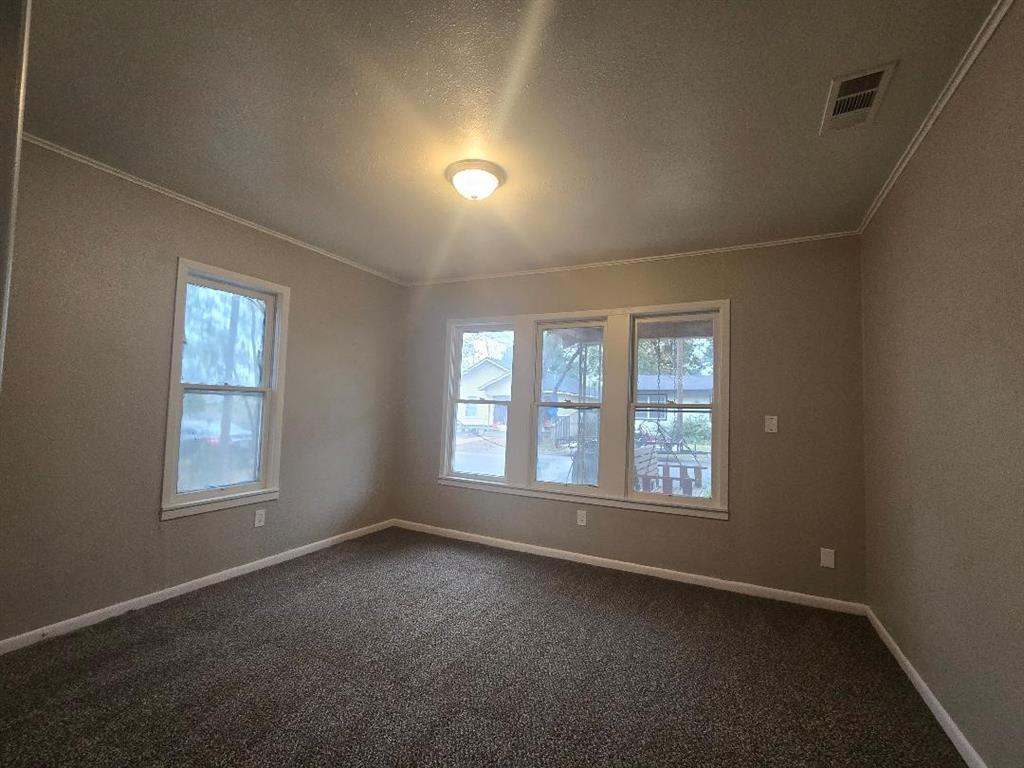 1126 West 6th Avenue Corsicana, TX 75110 - Photo 10 of 12 Empty room featuring ornamental molding, a textured ceiling, and dark carpet