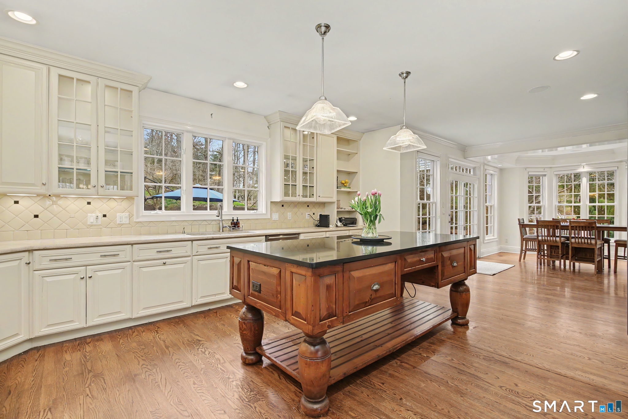 18 Brandon Circle Wilton, CT 06897 - Photo 18 of 40 a kitchen with granite countertop a stove a sink a dining table and chairs with wooden floor