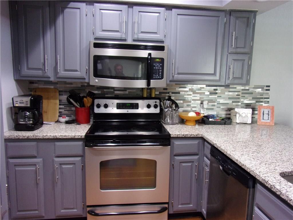 18240 Midway Road, Unit 105 Dallas, TX 75287 - Photo 4 of 37 a kitchen with granite countertop wood cabinets and stainless steel appliances