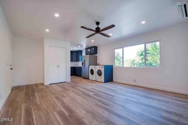 a view of an empty room with a window and wooden floor