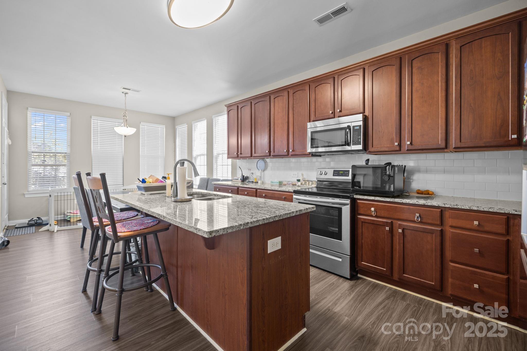 6416 Baltray Road Charlotte, NC 28278 - Photo 6 of 34 a kitchen with stainless steel appliances granite countertop wooden cabinets a dining table and chairs