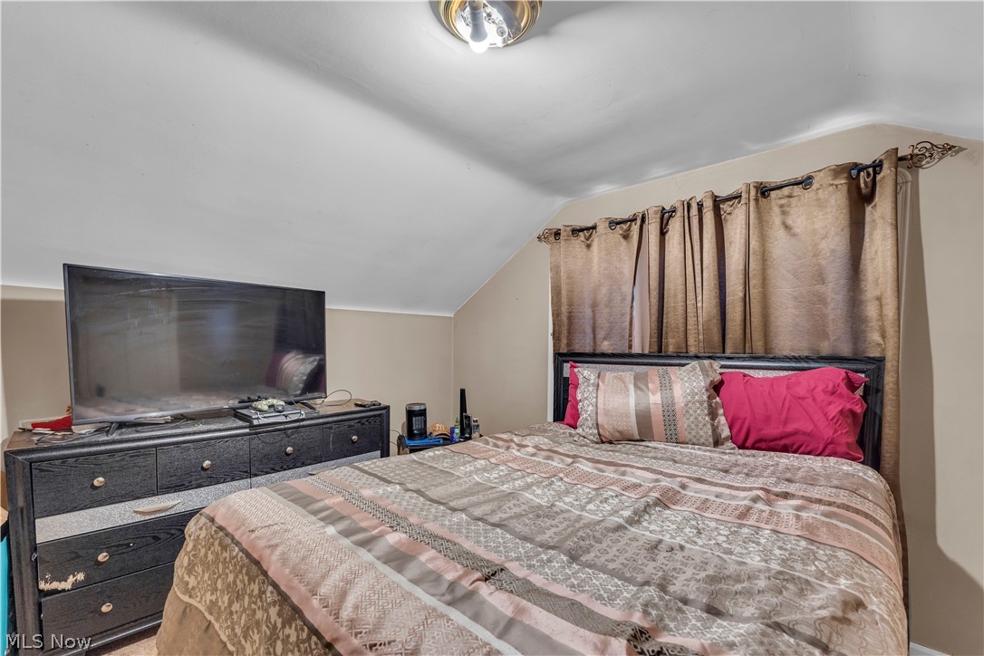 3962 Grosvenor Road South Euclid, OH 44118 - Photo 16 of 27 Angled ceiling bedroom featuring a flush mount ceiling light fixture, neutral wall paint, and window treatments with decorative finials