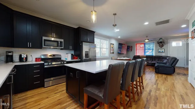 a kitchen with stainless steel appliances a table chairs refrigerator and microwave