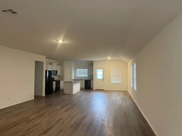 a view of a big room with wooden floor and windows