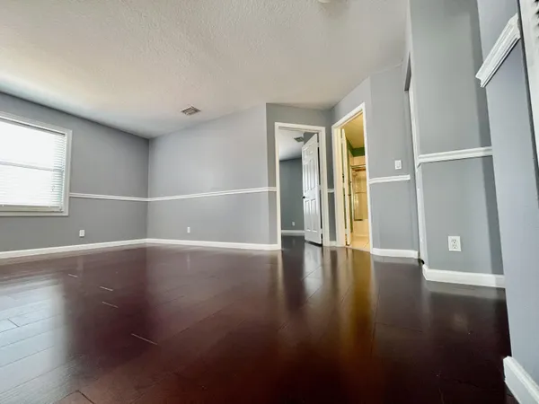 an empty room with wooden floor and windows