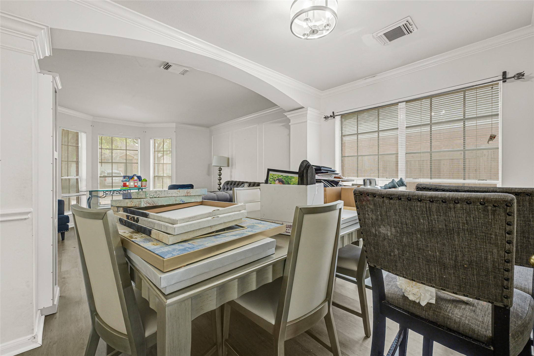6419 Slate Stone Street Houston, TX 77084 - Photo 10 of 49 This photo showcases a spacious dining and living area with large windows offering natural light. The room features crown molding, a mix of seating styles, and neutral tones, creating a versatile space for relaxation and entertainment.