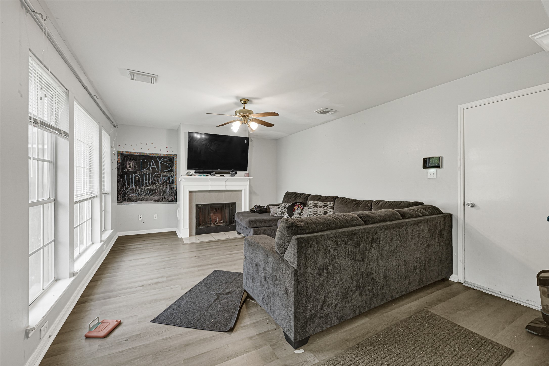 6419 Slate Stone Street Houston, TX 77084 - Photo 16 of 49 Bright living room with large windows, modern flooring, and a cozy fireplace. Features a ceiling fan, wall-mounted TV, and spacious sectional sofa ideal for relaxation.