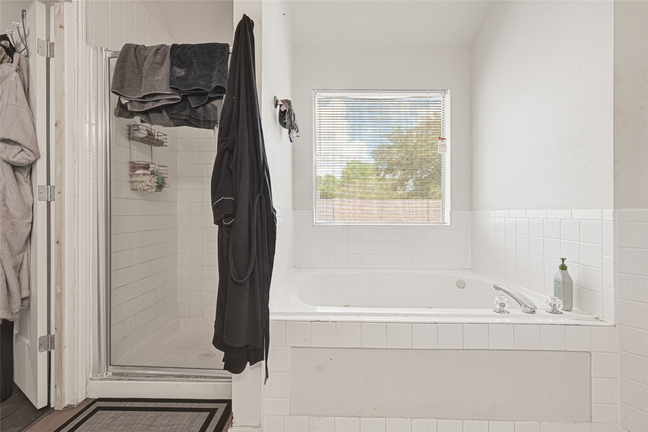 6419 Slate Stone Street Houston, TX 77084 - Photo 23 of 49 This bathroom features a spacious soaking tub under a bright window and a separate tiled shower, providing a comfortable and inviting space for relaxation.