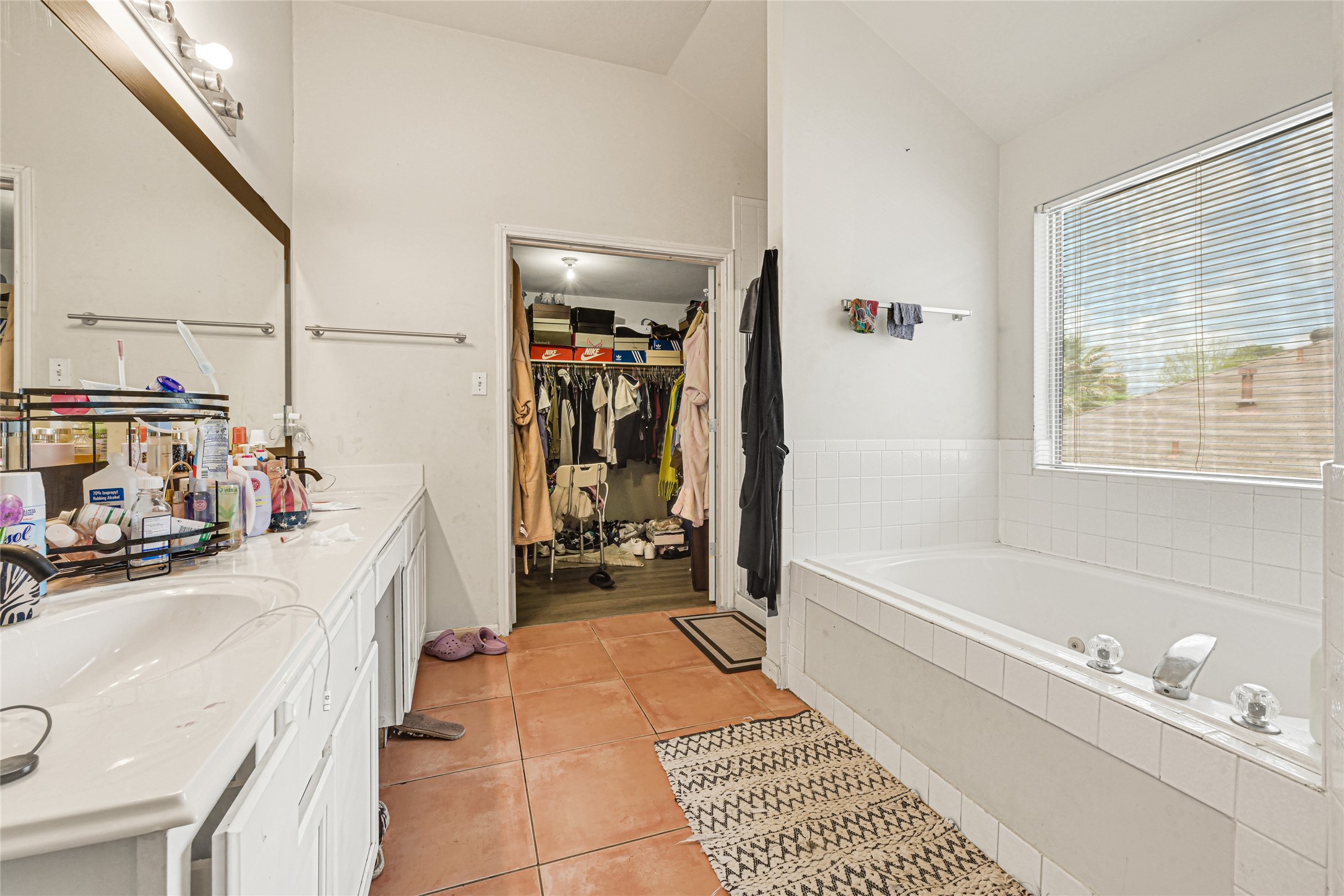 6419 Slate Stone Street Houston, TX 77084 - Photo 27 of 49 This spacious bathroom features a large soaking tub with a window, dual sinks with ample counter space, and an adjoining walk-in closet for convenient storage. Bright and functional, ideal for relaxation and organization.