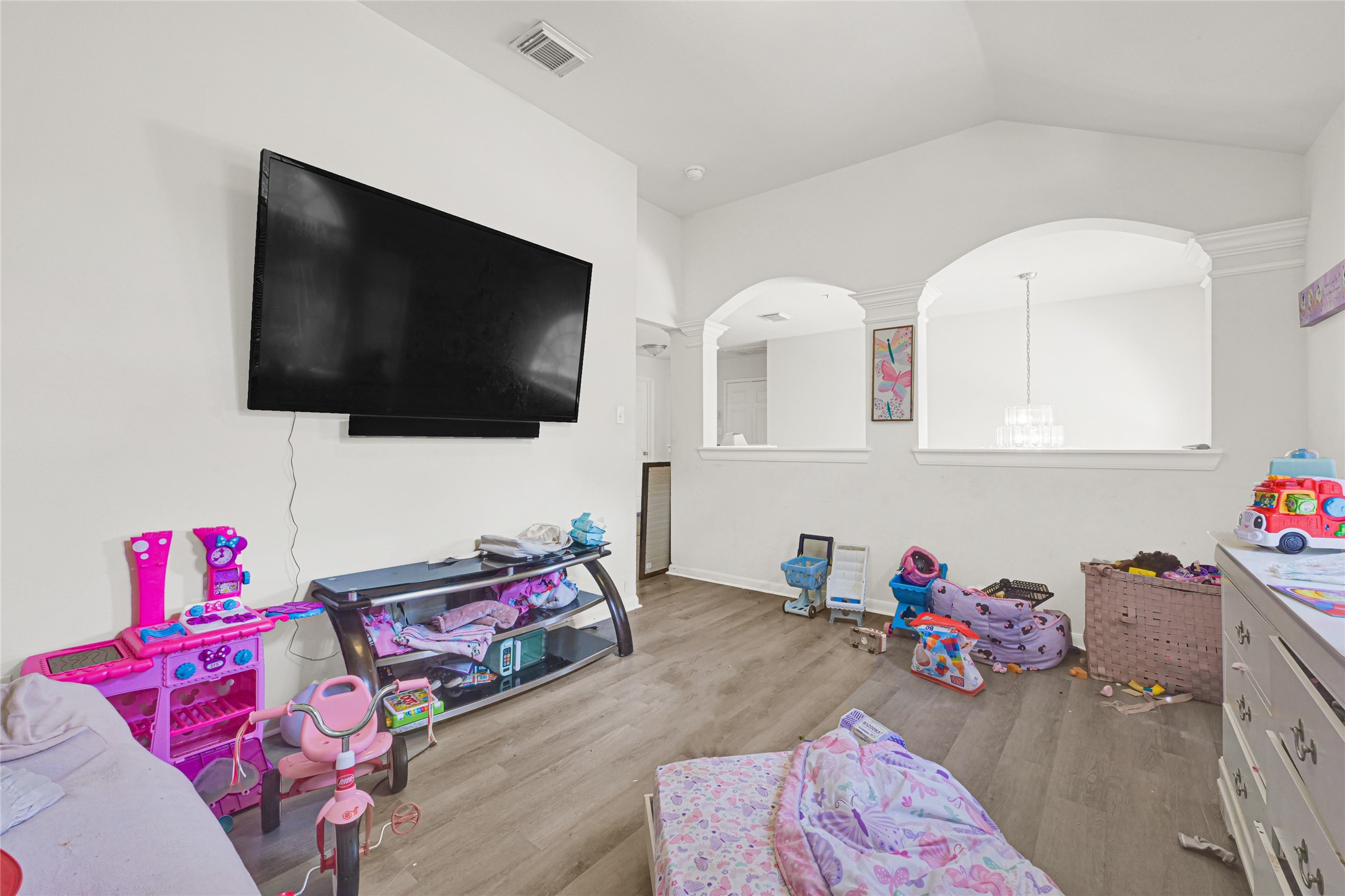 6419 Slate Stone Street Houston, TX 77084 - Photo 29 of 49 This room features a cozy space with laminate flooring, a wall-mounted TV, and built-in shelving. It’s perfect for a playroom or family area, with open archways providing a view into the adjacent room, enhancing the open and airy feel.