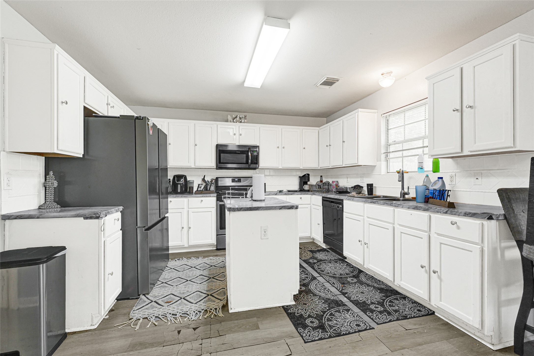 6419 Slate Stone Street Houston, TX 77084 - Photo 2 of 49 Bright and spacious kitchen with modern stainless steel appliances, abundant white cabinetry, dark countertops, and large windows for natural light.
