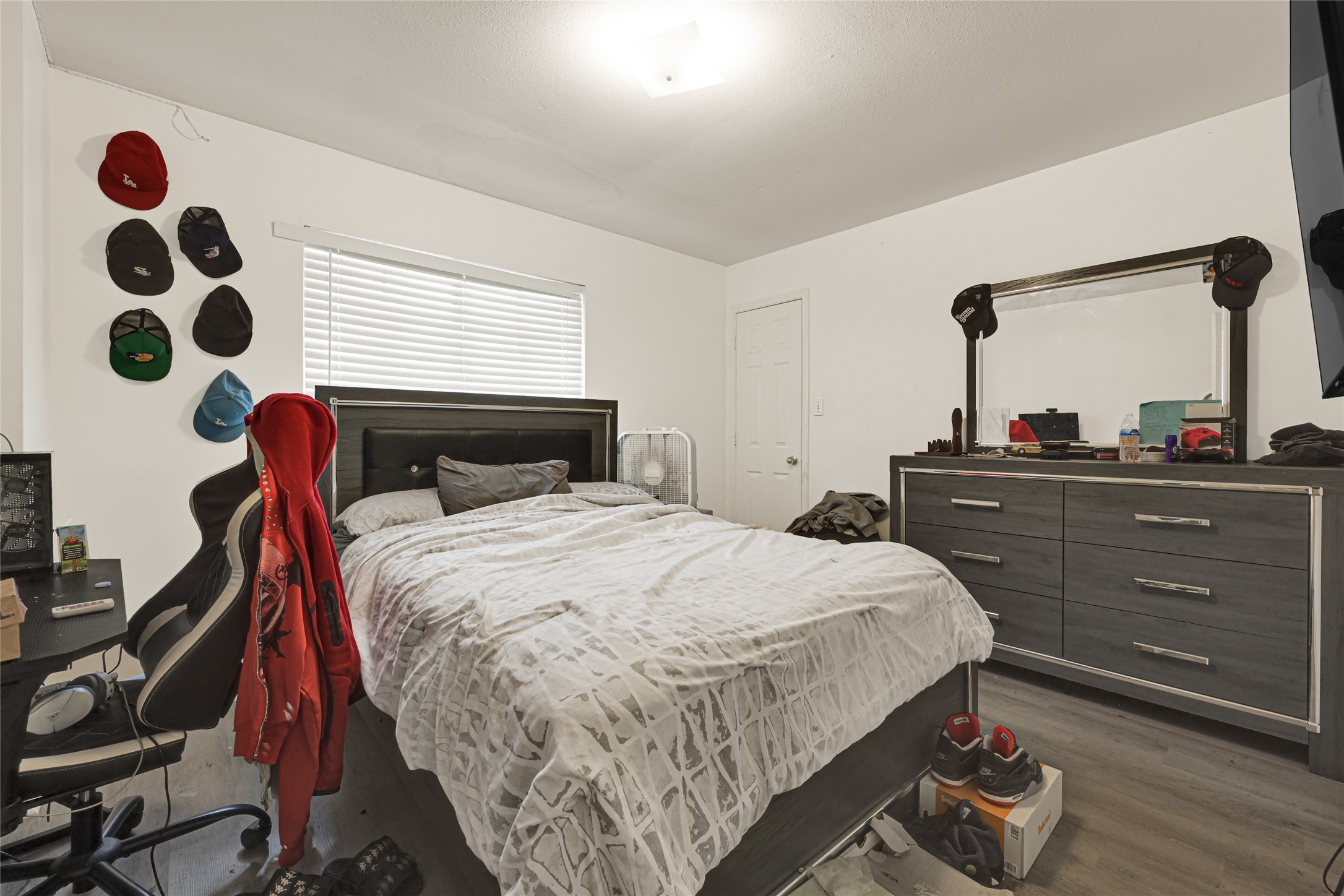 6419 Slate Stone Street Houston, TX 77084 - Photo 42 of 49 This bedroom features a spacious layout with a comfortable bed, a modern dresser with a mirror, and a small workspace. The room is well-lit with natural light from the window, and the walls are adorned with a collection of hats. The decor is simple and functional, offering a cozy atmosphere.