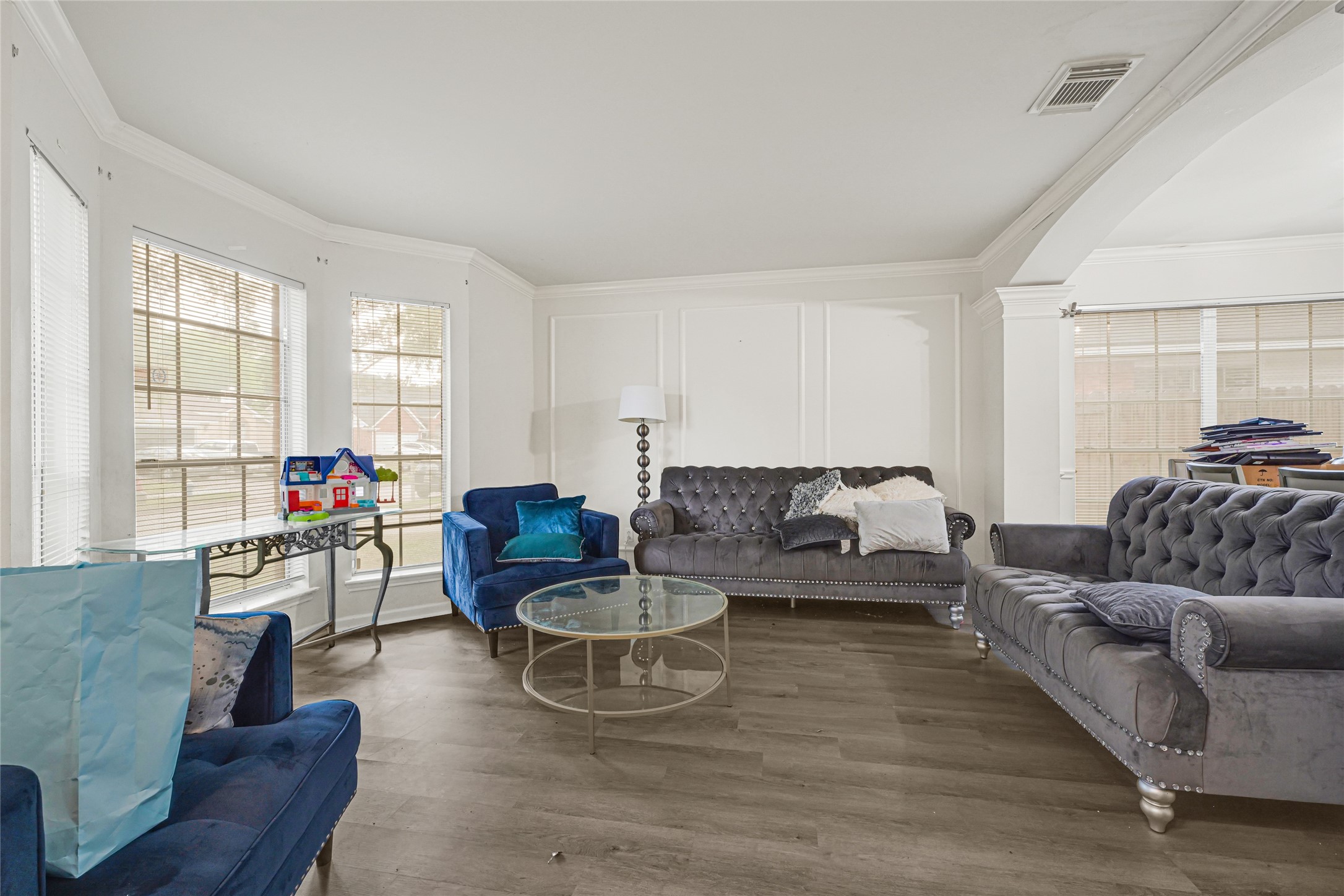 6419 Slate Stone Street Houston, TX 77084 - Photo 6 of 49 This spacious living room features elegant tufted sofas, abundant natural light through large windows, and hardwood flooring, creating a cozy and inviting atmosphere.