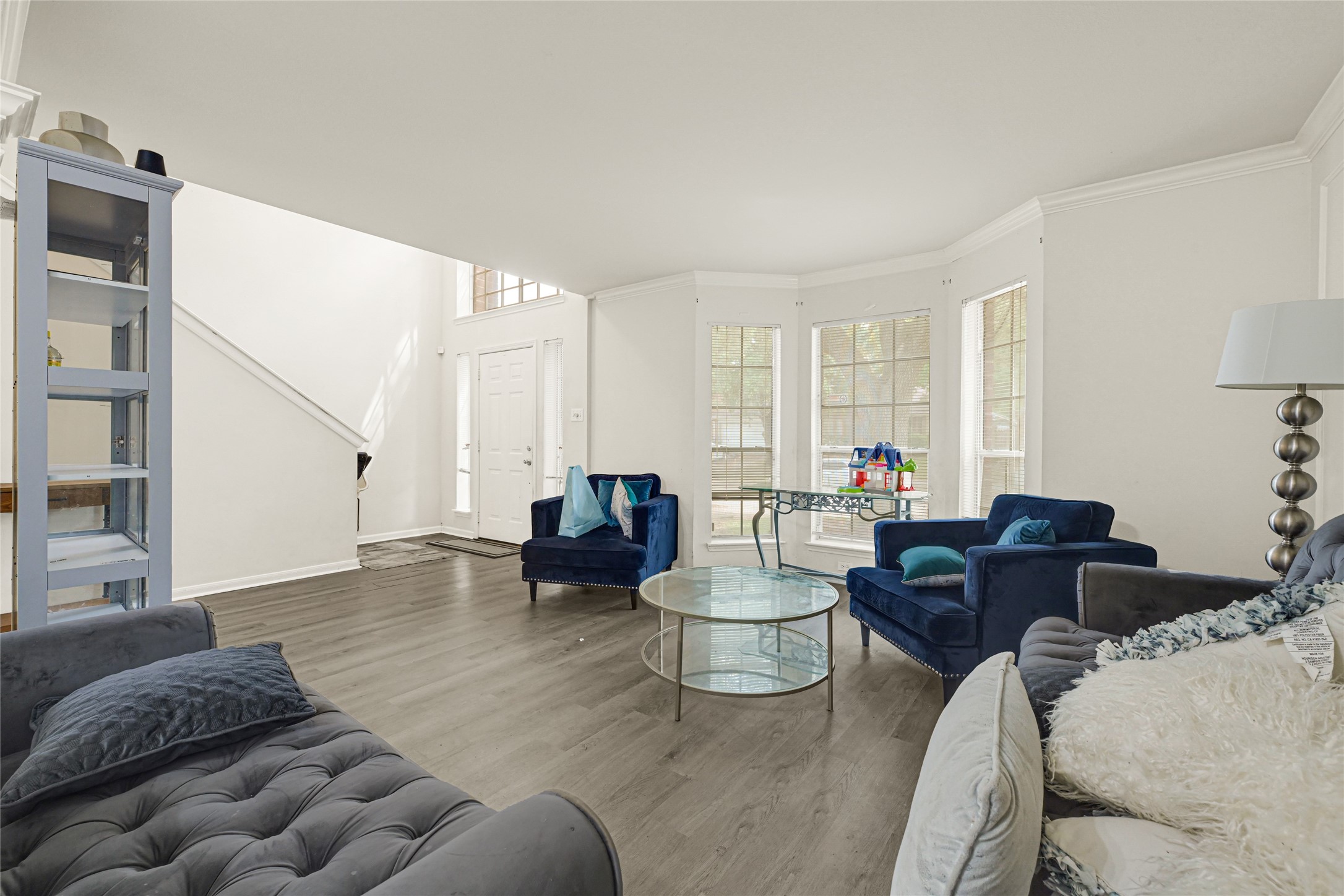 6419 Slate Stone Street Houston, TX 77084 - Photo 7 of 49 This inviting living room features modern flooring, ample natural light from large windows, and a cozy seating area. A staircase leads to the upper level, and the entryway is bright and welcoming.