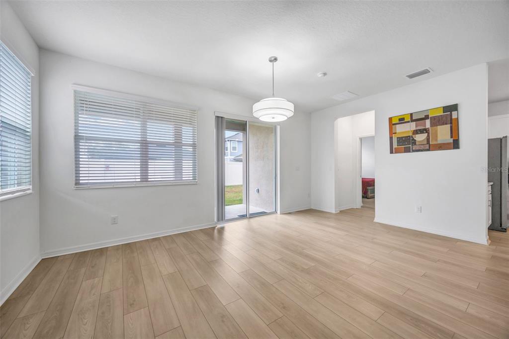 7882 Lennox Loop Wesley Chapel, FL 33544 - Photo 16 of 58 an empty room with wooden floor chandelier and windows