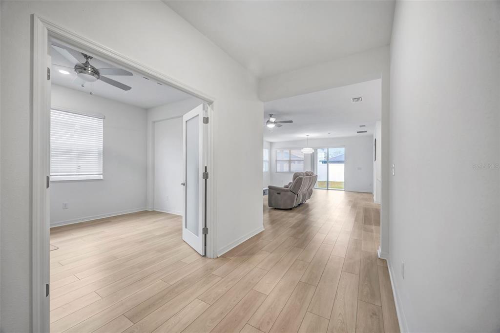 7882 Lennox Loop Wesley Chapel, FL 33544 - Photo 29 of 58 a view of a hallway with wooden floor a glass table and chairs