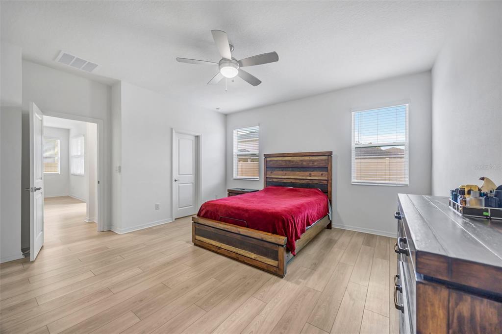 7882 Lennox Loop Wesley Chapel, FL 33544 - Photo 35 of 58 a spacious bedroom with a bed and wooden floor