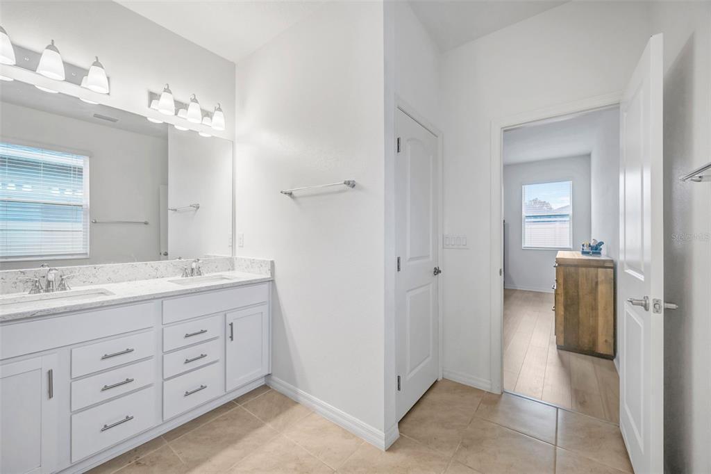 7882 Lennox Loop Wesley Chapel, FL 33544 - Photo 41 of 58 a spacious bathroom with a granite countertop sink a mirror and a shower