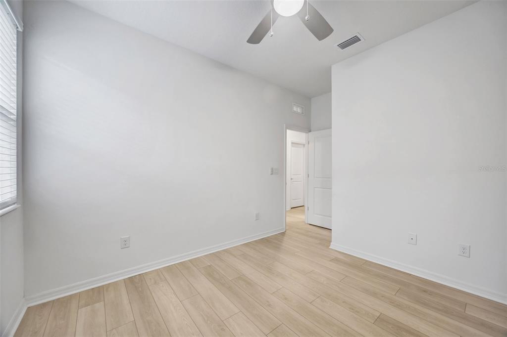7882 Lennox Loop Wesley Chapel, FL 33544 - Photo 50 of 58 an empty room with a ceiling fan and wooden floor