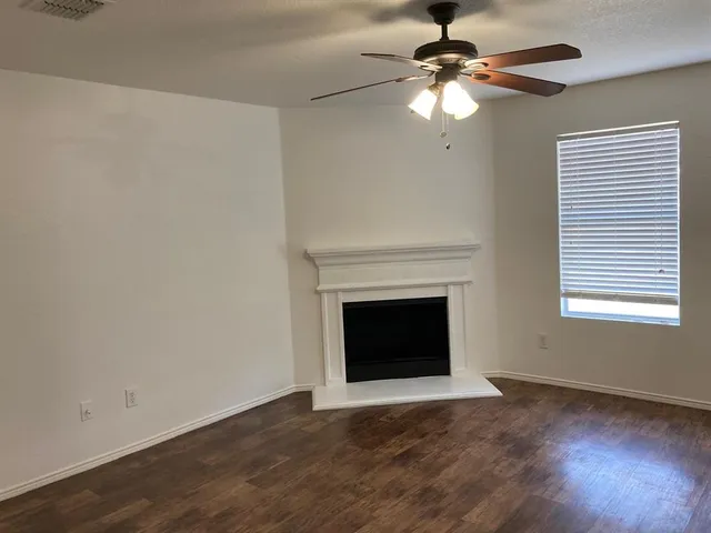 a view of a livingroom with a fireplace a chandelier fan and wooden floor