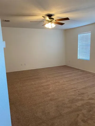 a view of an empty room with chandelier fan