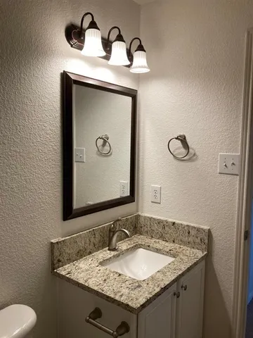 a bathroom with a granite countertop sink and a mirror