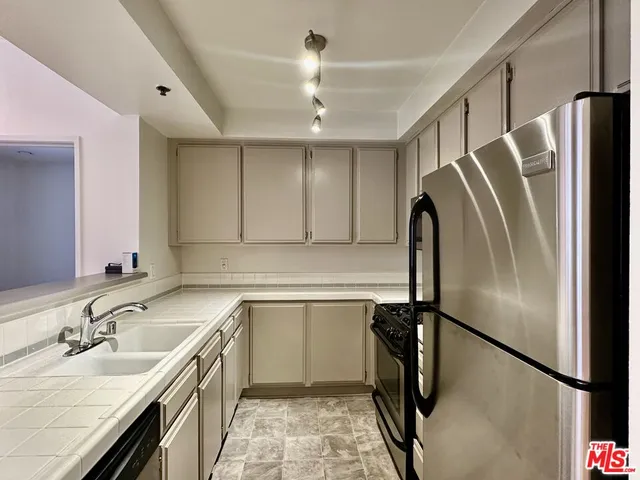 a kitchen with stainless steel appliances granite countertop a refrigerator a sink and a stove