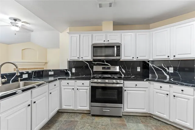 a kitchen with white cabinets and appliances